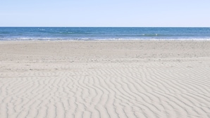 A sandy beach with gentle waves and a clear sky. - Camping Azahar (Benicassim)