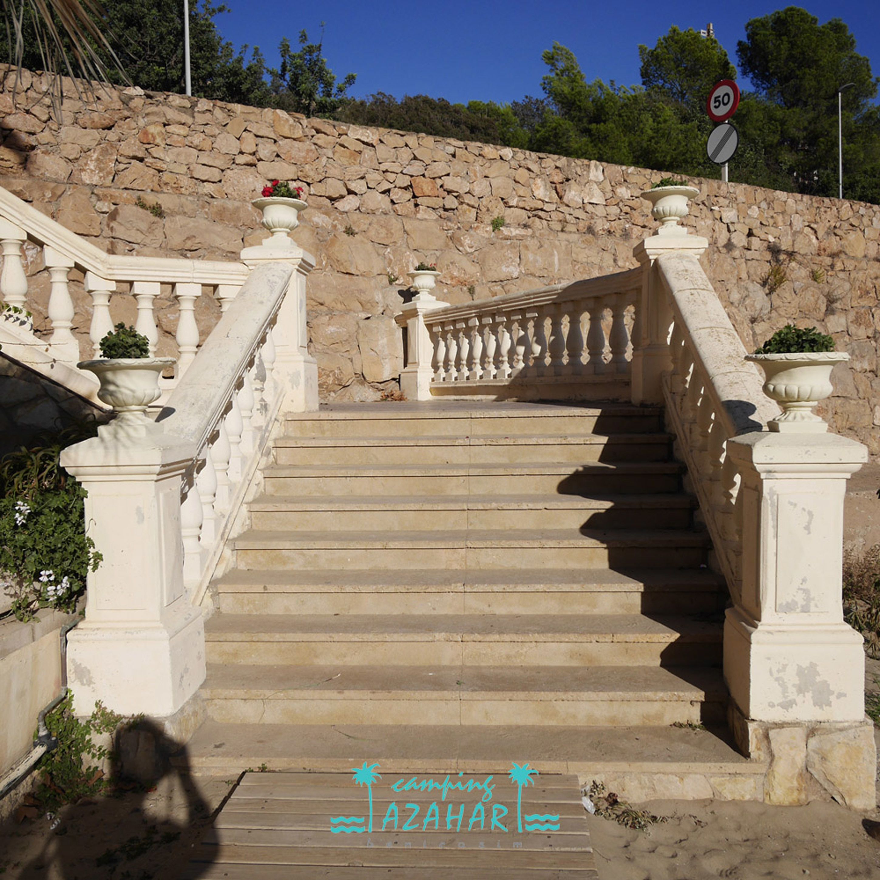 A stone staircase with white balustrades and potted plants at the top.