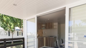 A modern kitchen with sliding glass doors, a dining area with a table and chairs, and a wooden deck. - Camping Azahar (Benicassim)