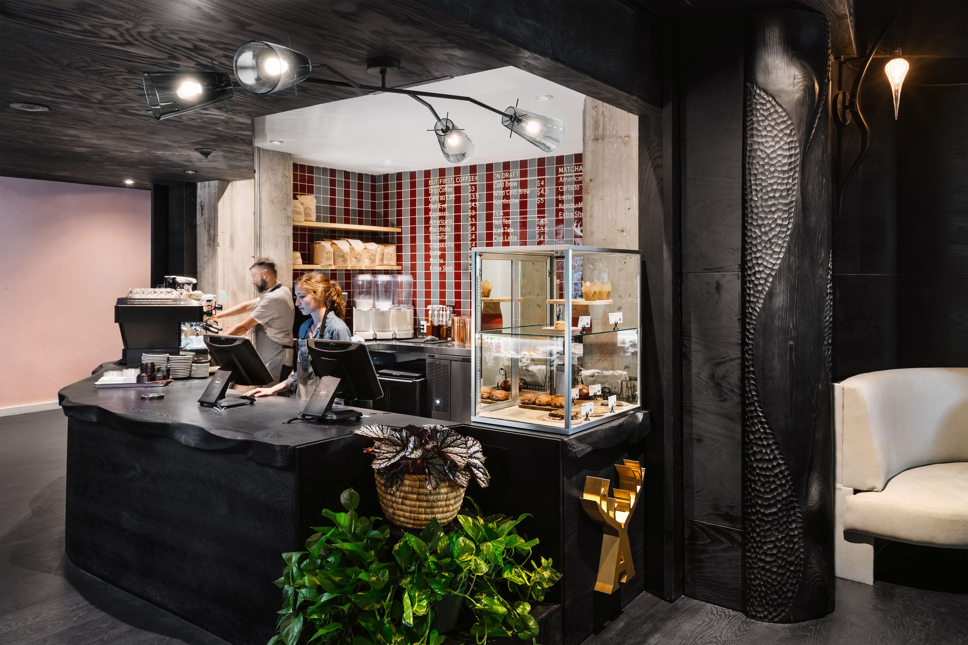 A reception area with a black counter, a glass display case, and a seating area with a white chair.