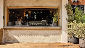 An outdoor bar area with a concrete counter, potted plants, and a wooden ceiling. - The LINE Austin (Austin)
