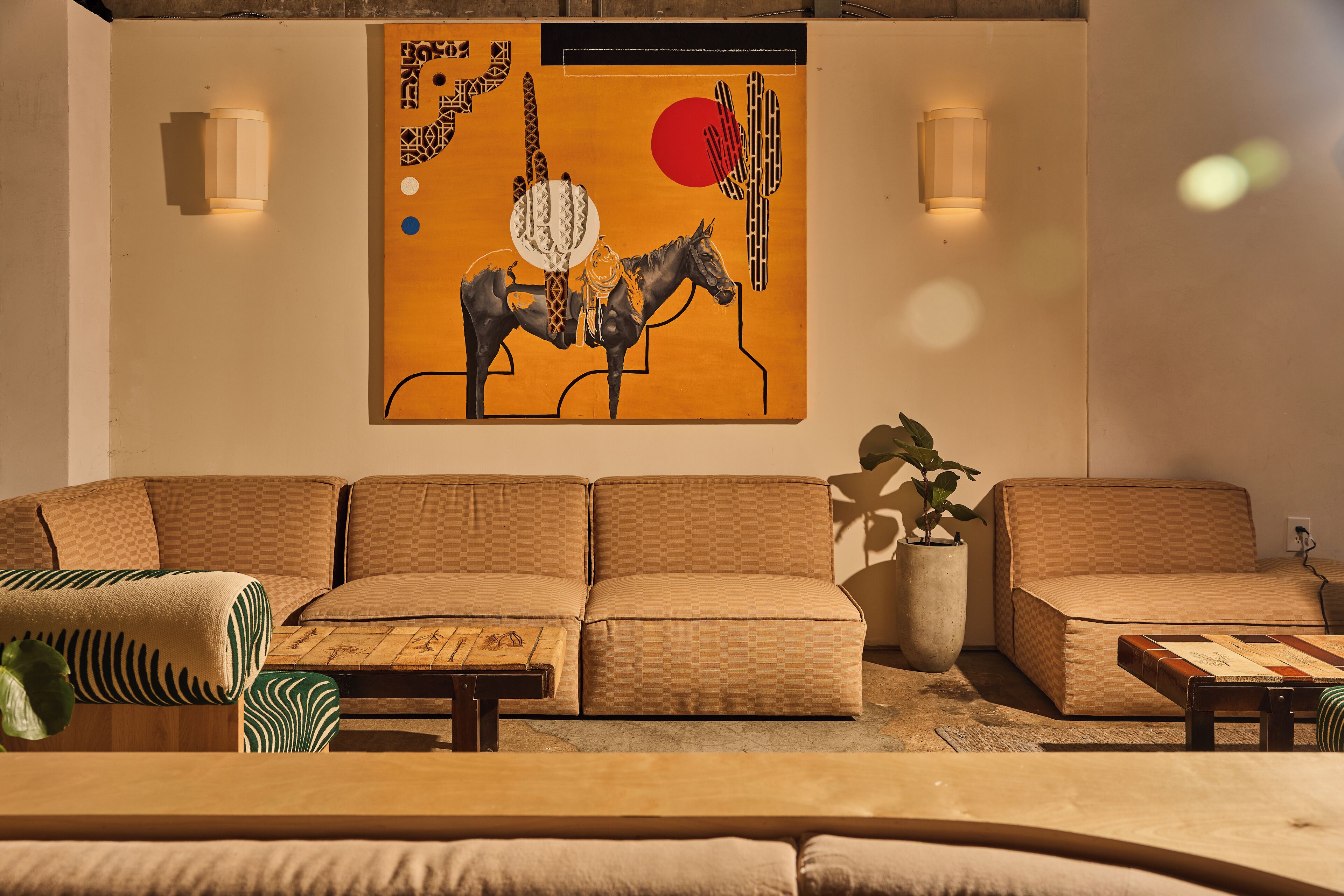 A modern living room with a large sofa, a coffee table, and a wall-mounted artwork.
