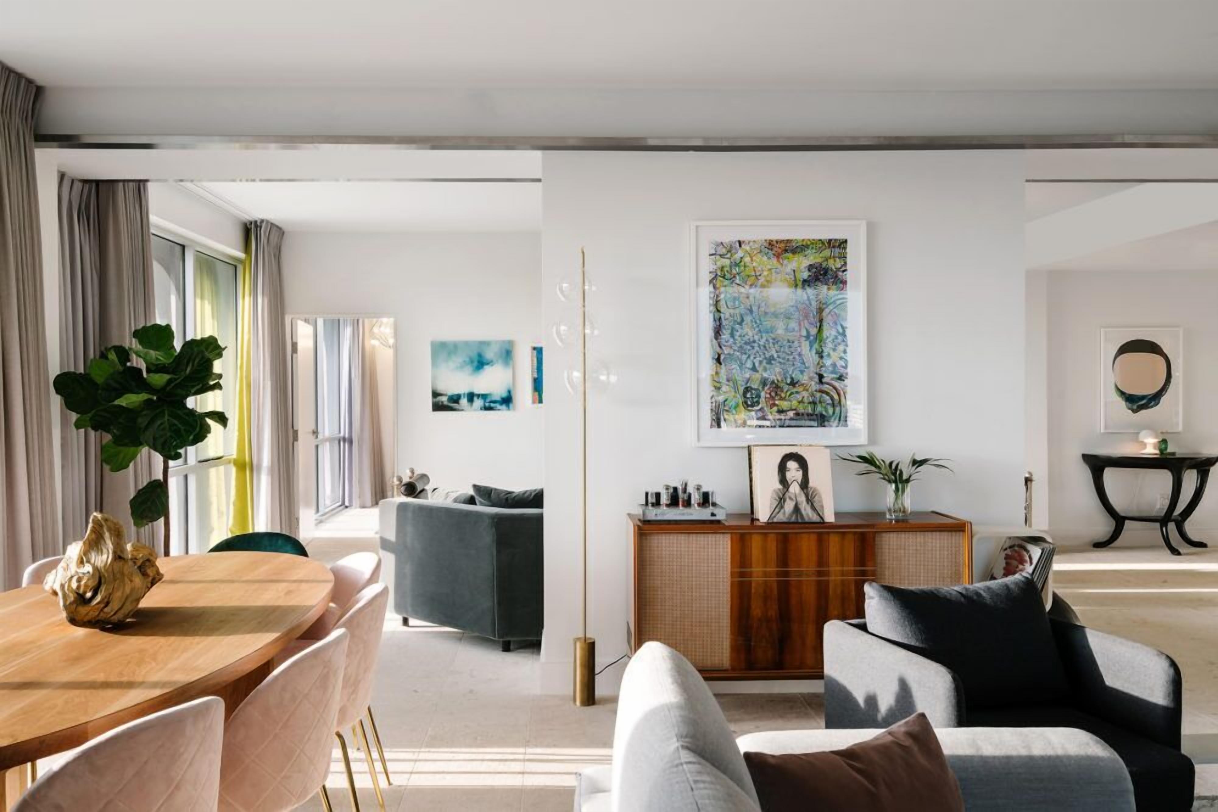 Ein modernes Wohnzimmer mit Essbereich, mit einem Holztisch, Stühlen, einer Couch und einem großen Gemälde an der Wand.