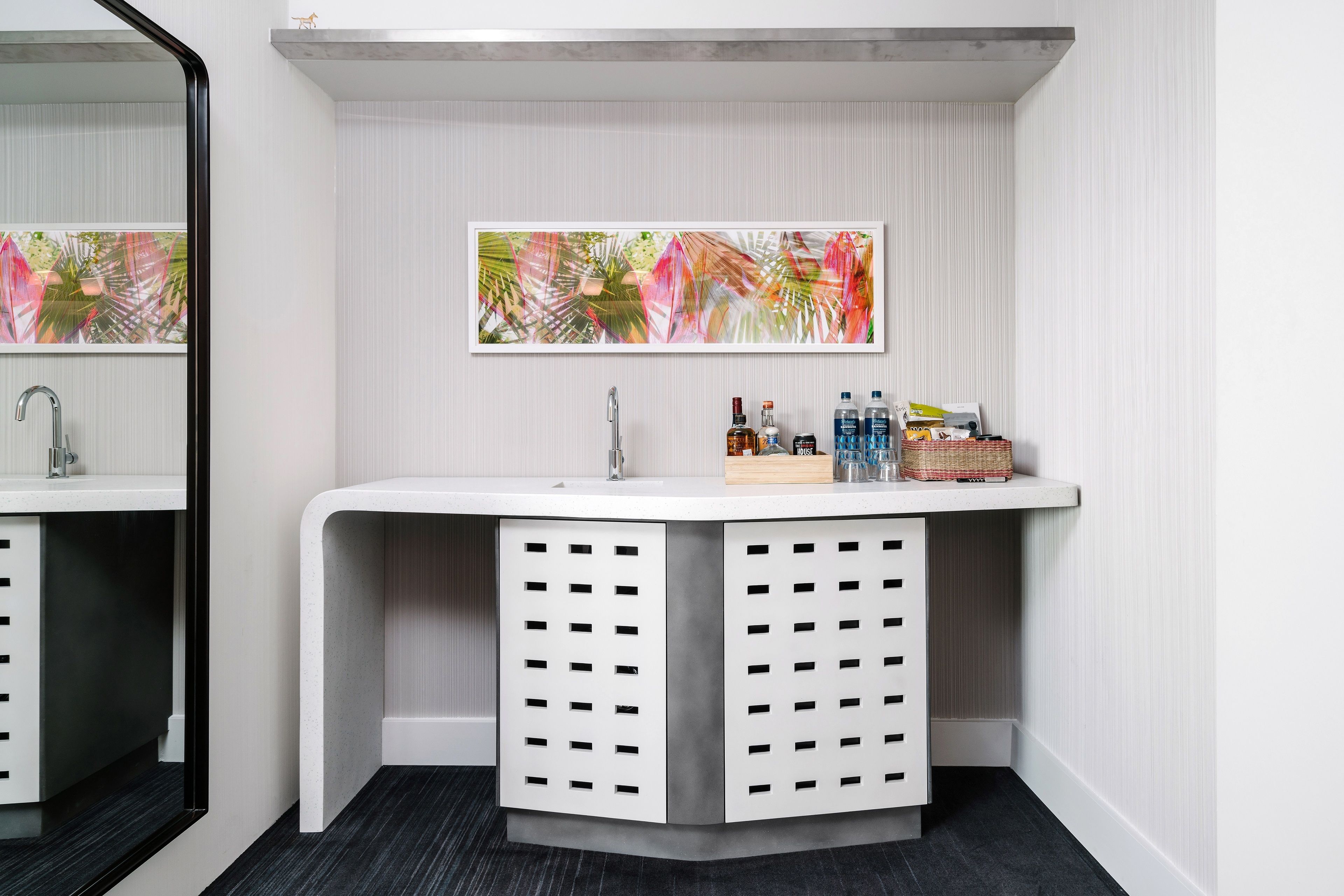 A modern bathroom with a white vanity, a large mirror, and a decorative wall art piece.