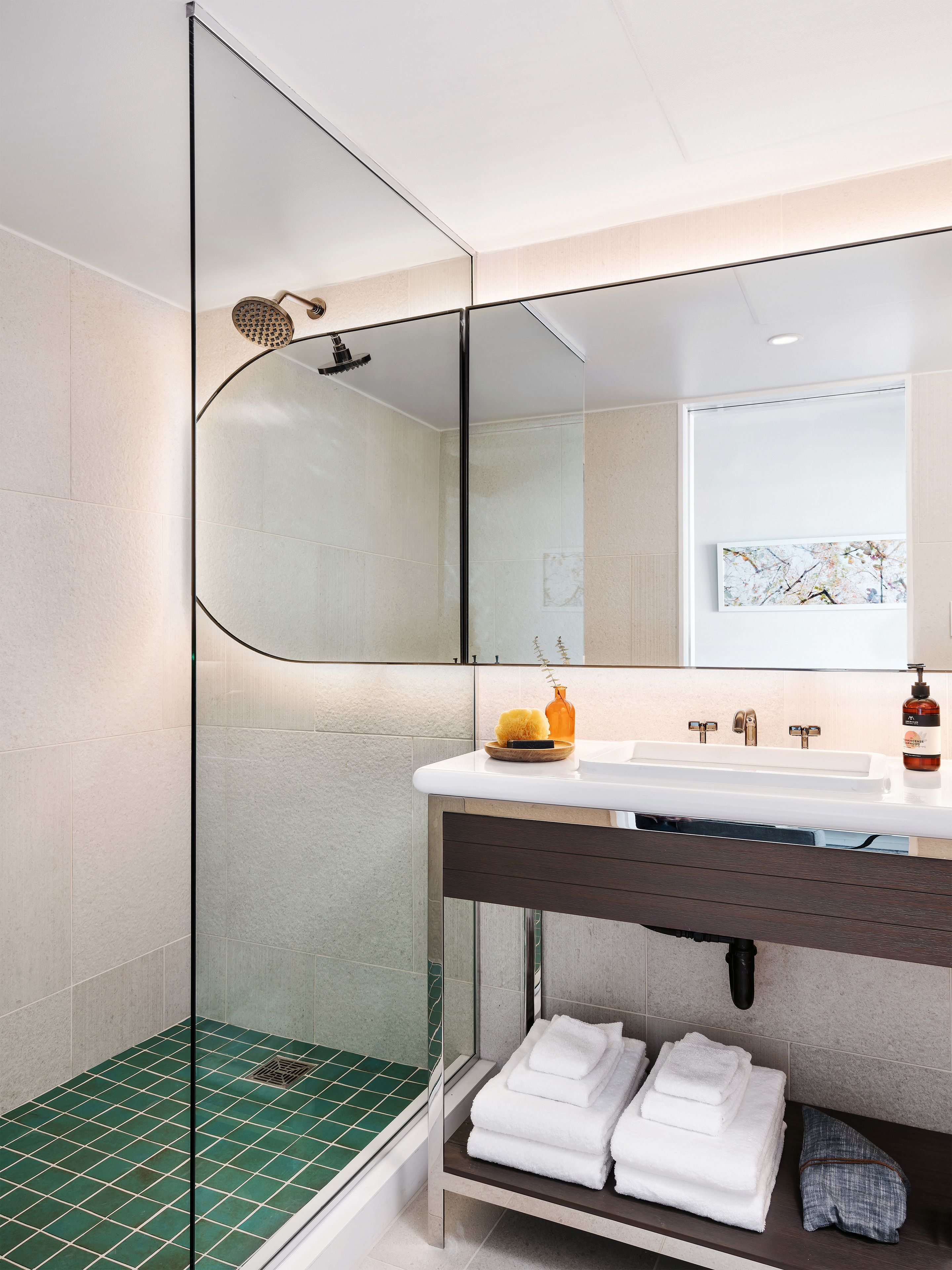 A modern bathroom with a glass-enclosed shower, a white sink, and a mirror above it.