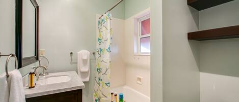 A bathroom with a sink, mirror, shower curtain, and a toilet.