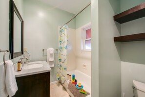 Ein Badezimmer mit Waschbecken, Spiegel, Duschvorhang und Toilette.