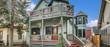 A two-story house with a balcony, a front porch, and a staircase leading to the second floor.