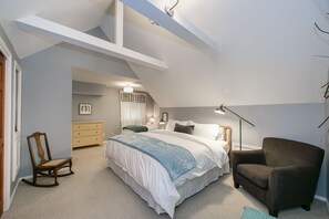 Ein Schlafzimmer mit einem großen Bett, einem Schaukelstuhl, einem Sessel, einer Kommode und einer Stehlampe.