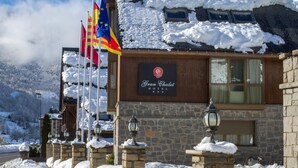 Un edificio de hotel con paredes de piedra, un letrero y varias banderas.