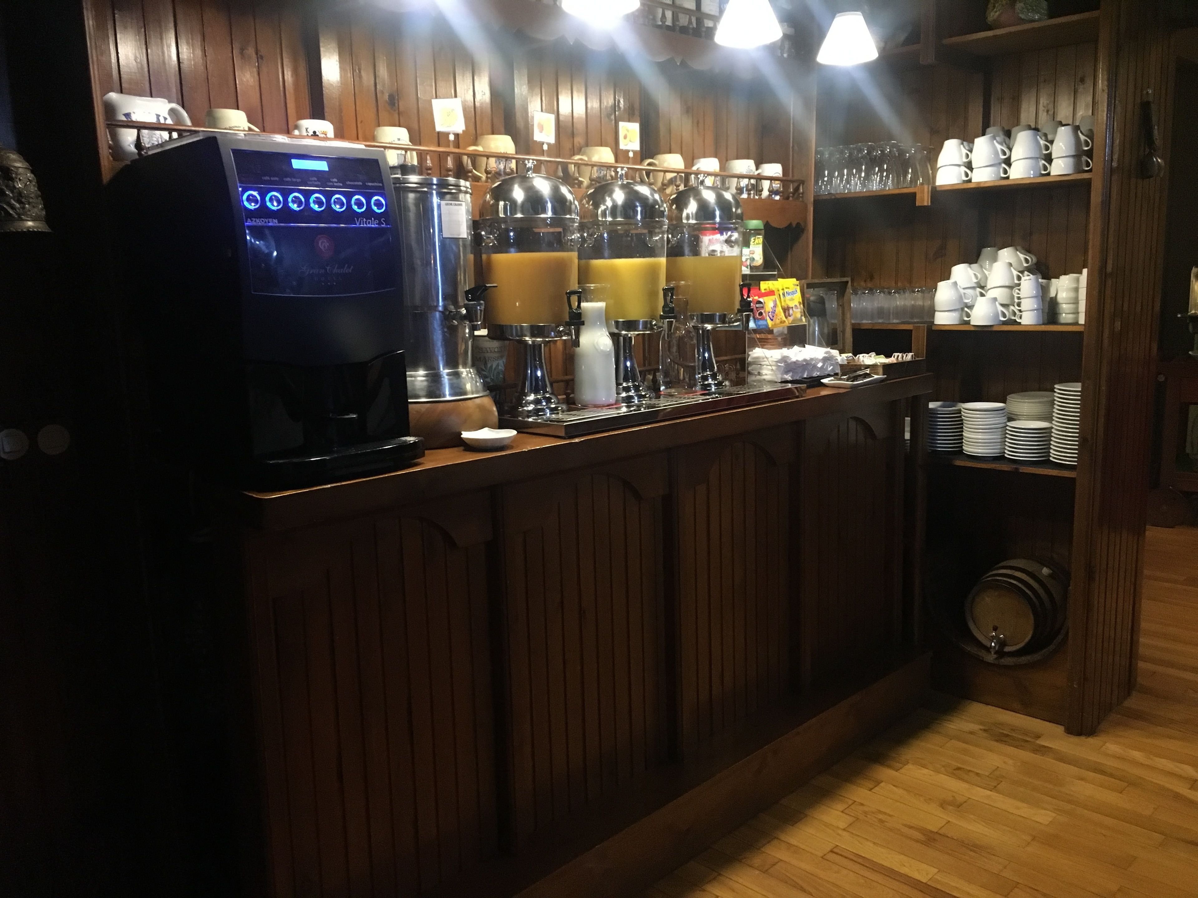 Una cafetería con una máquina de café, espumador de leche y varios vasos y tazas.