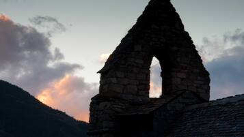 Una estructura de arco de piedra con techo, con un cielo nublado y una montaña al fondo.
