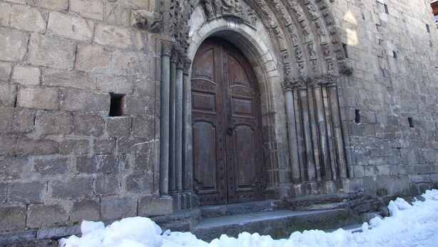 Un edificio de piedra con una puerta de madera grande y tallas intrincadas.