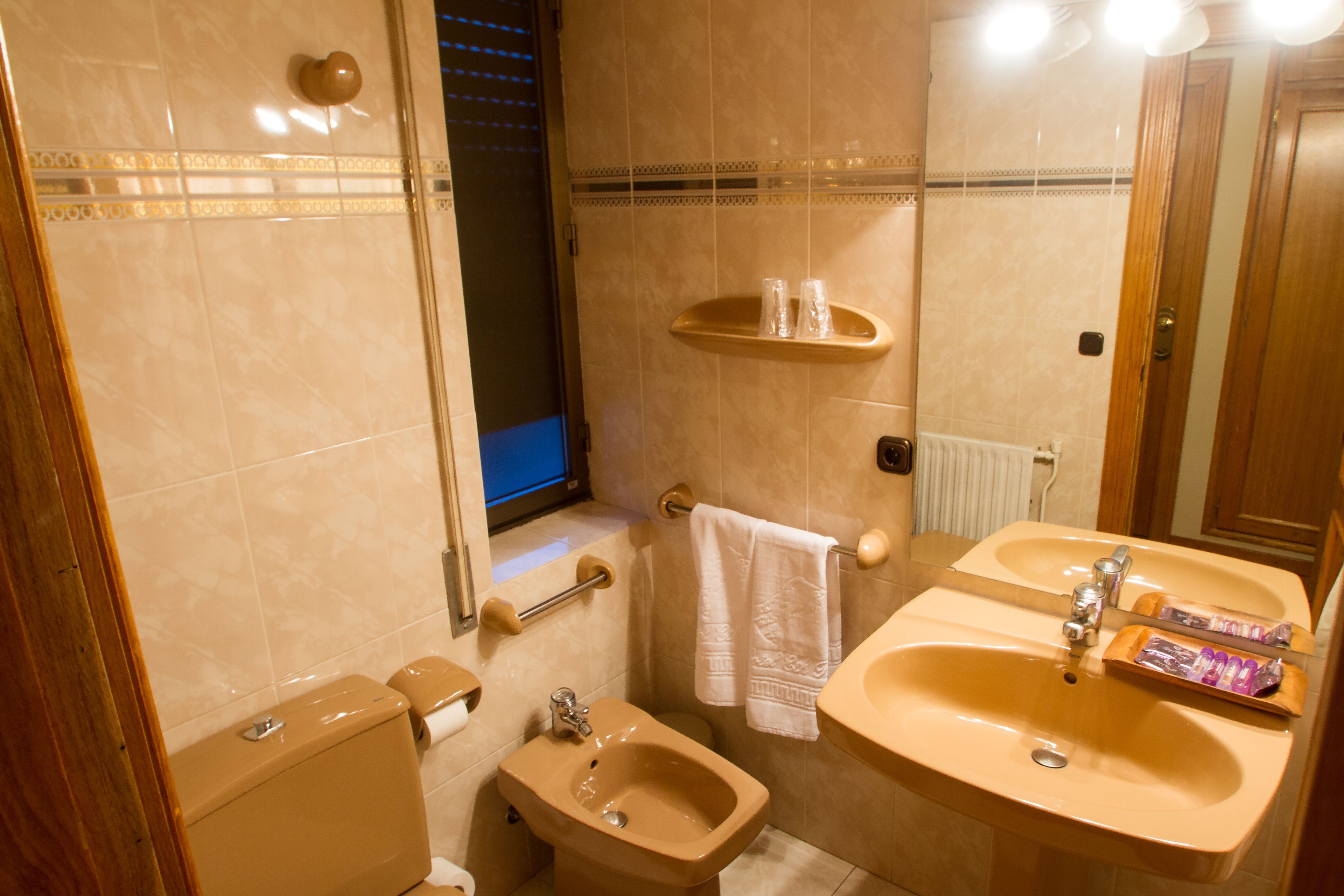 A bathroom with a toilet, bidet, sink, and mirror.