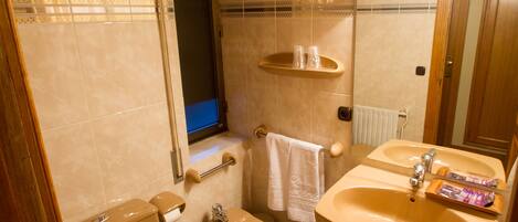 A bathroom with a toilet, bidet, sink, and mirror.
