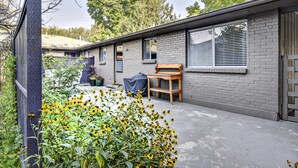 A modern house with a brick exterior, large windows, and a covered patio area with a wooden bench. - The East End Retreat (Boise)
