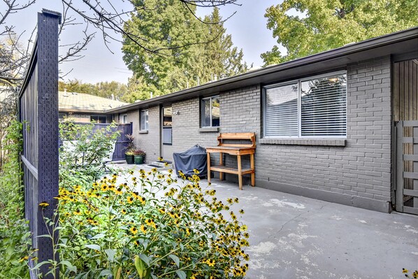 Une maison moderne avec une façade en briques, de grandes fenêtres et un patio couvert agrémenté d’un banc en bois.