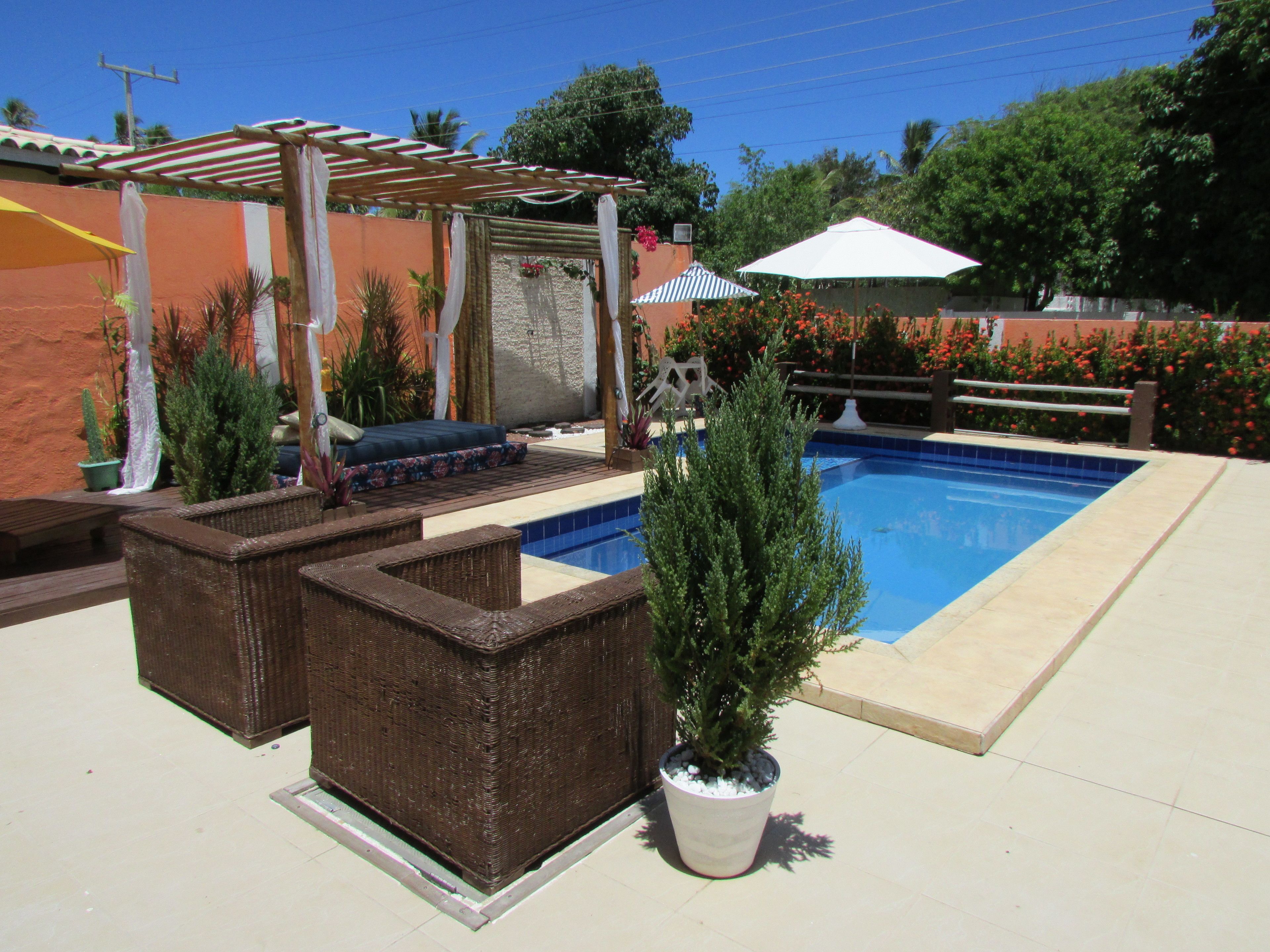 Un área de piscina con una pérgola, asientos y plantas en macetas.