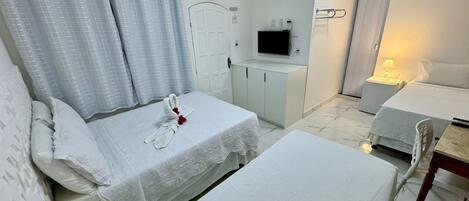 A hotel room with two beds, a TV, a desk, and a bathroom.
