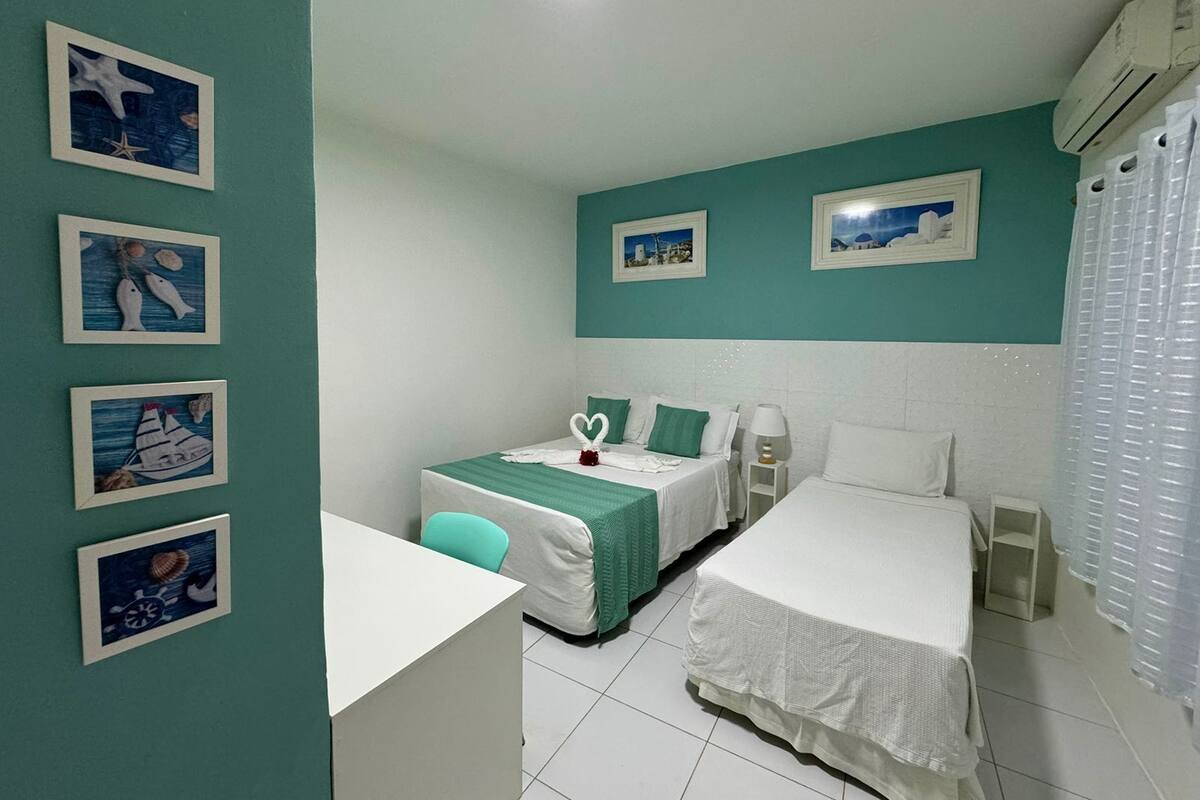 Een hotelkamer met twee bedden, een bureau en een stoel. Er hangen ingelijste foto’s aan de muur.