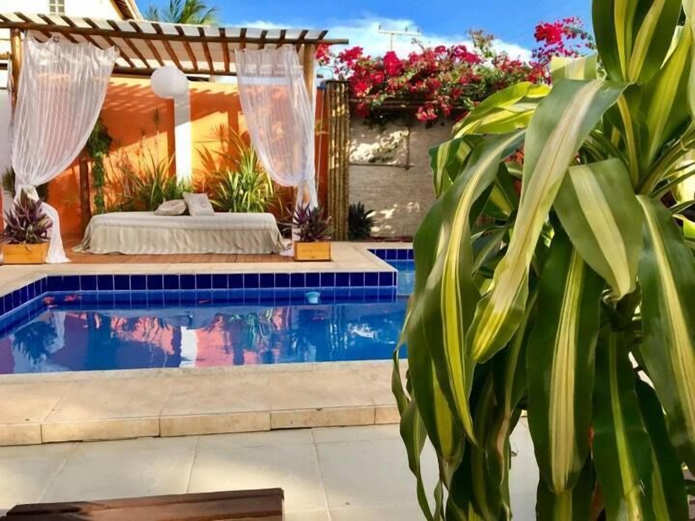 A pool area with a sunlit outdoor seating area, a tiled pool, and lush greenery.