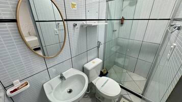 Ein modernes Badezimmer mit Waschbecken, Toilette und Duschkabine aus Glas.
