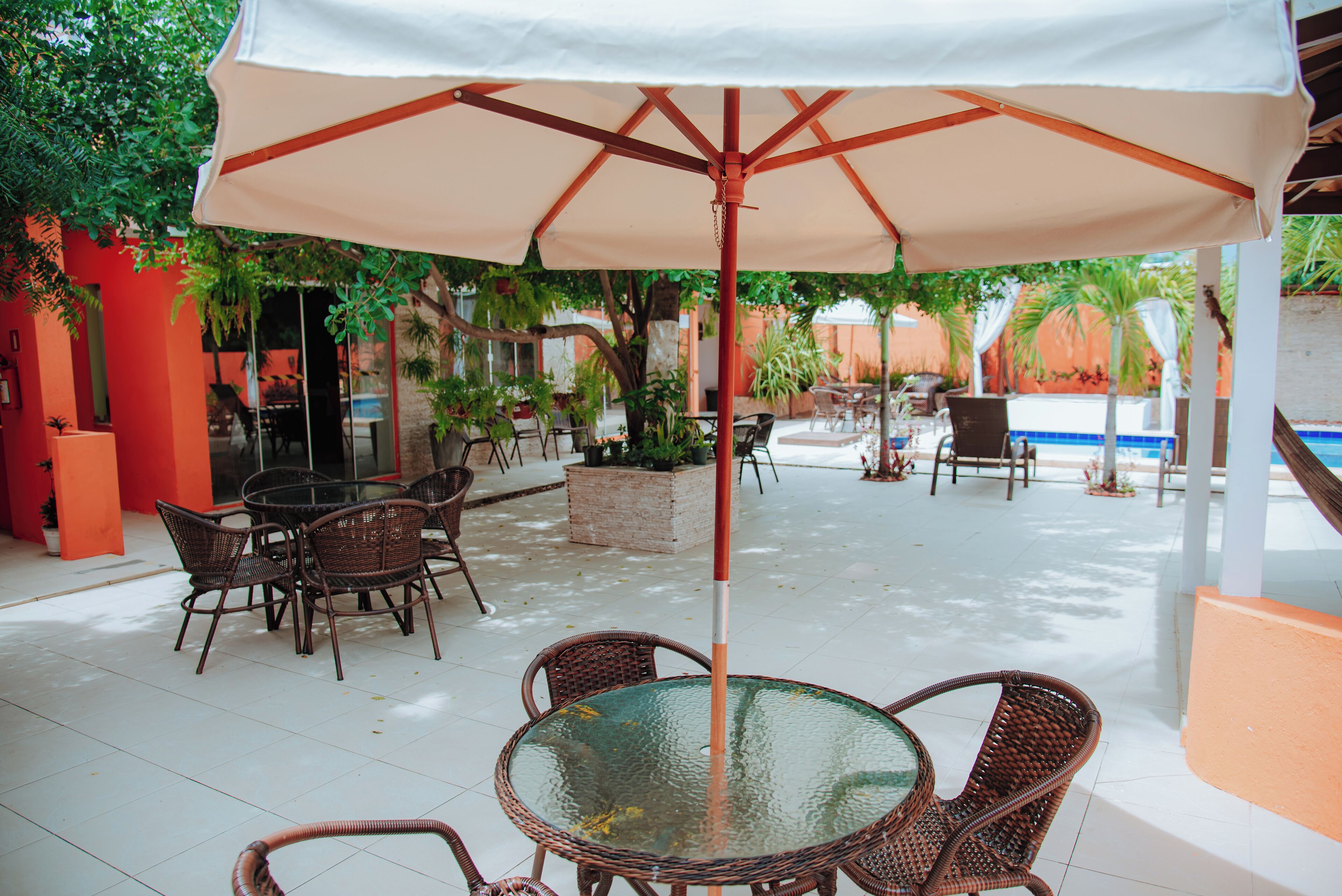An outdoor patio with wicker furniture, a glass table, and a large umbrella.