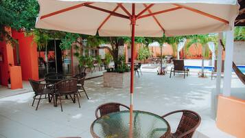 An outdoor patio with wicker furniture, a glass table, and a large umbrella.