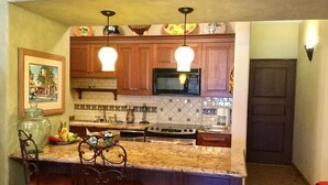 A kitchen with wooden cabinets, a granite countertop, a microwave, a stove, and two pendant lights.
