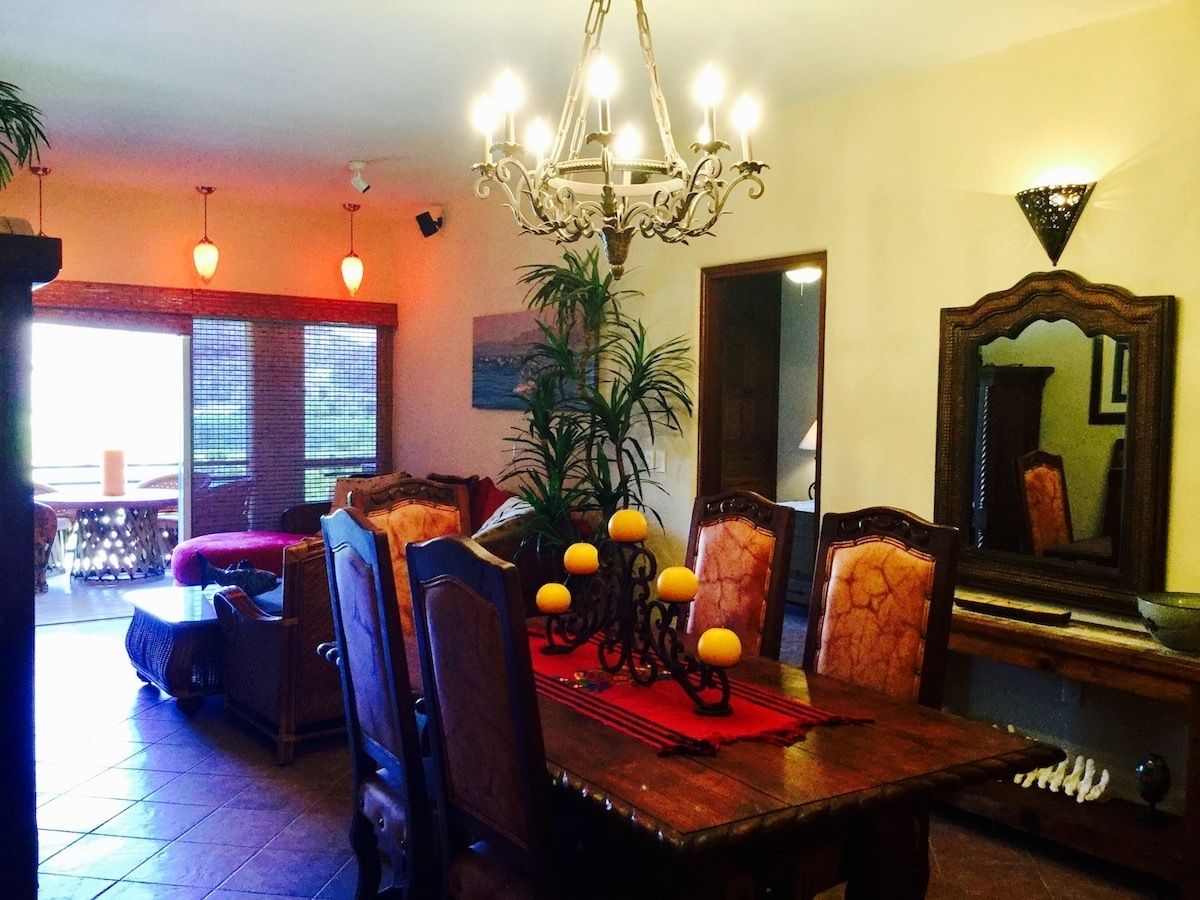 A dining area with a chandelier, chairs, a table, and a mirror.