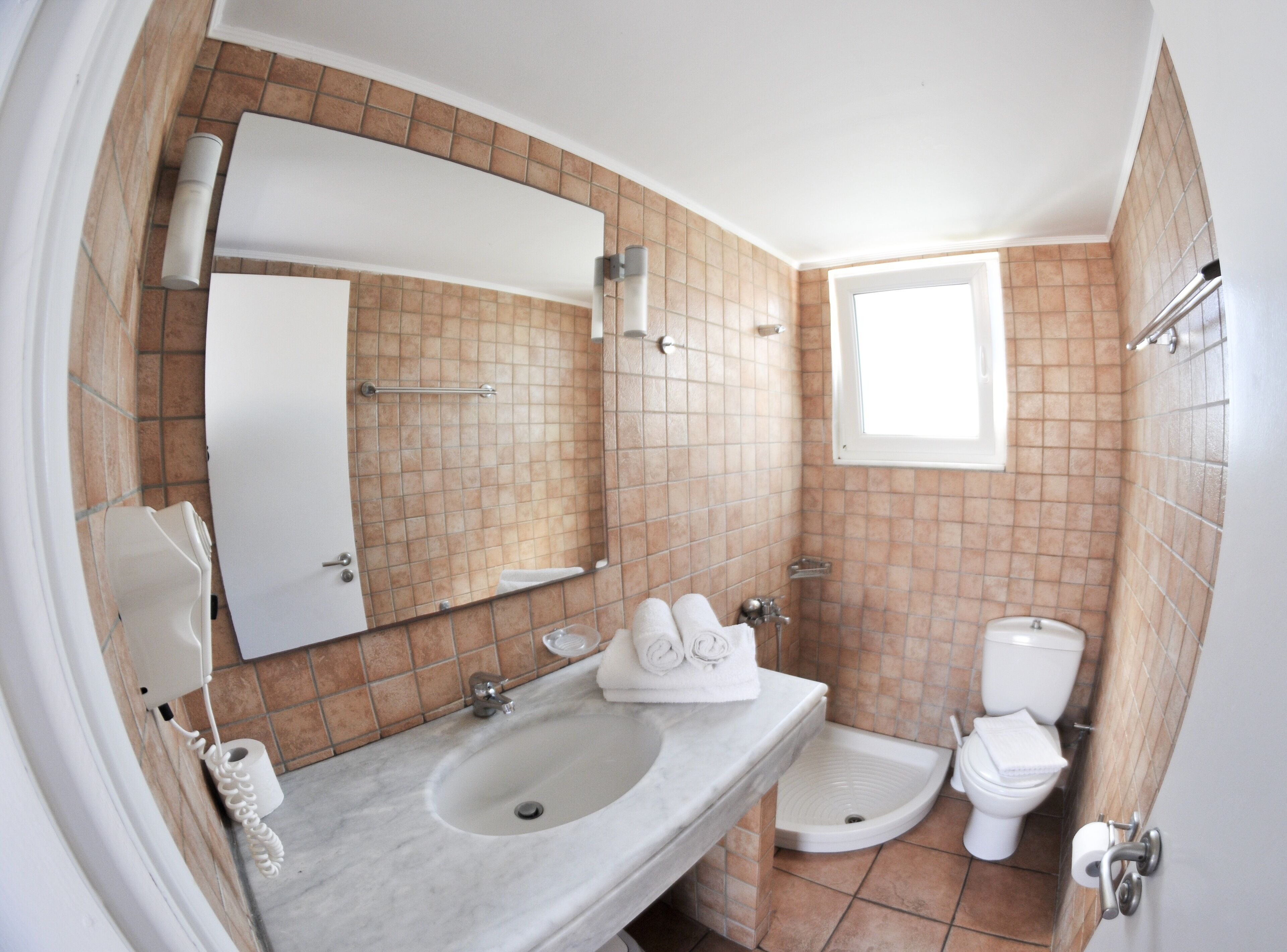 A bathroom with a sink, mirror, towel rack, toilet, and a window.