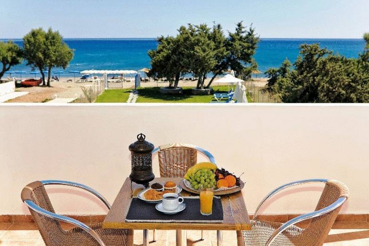 Una mesa con alimentos para el desayuno, vista al mar y asientos al aire libre.