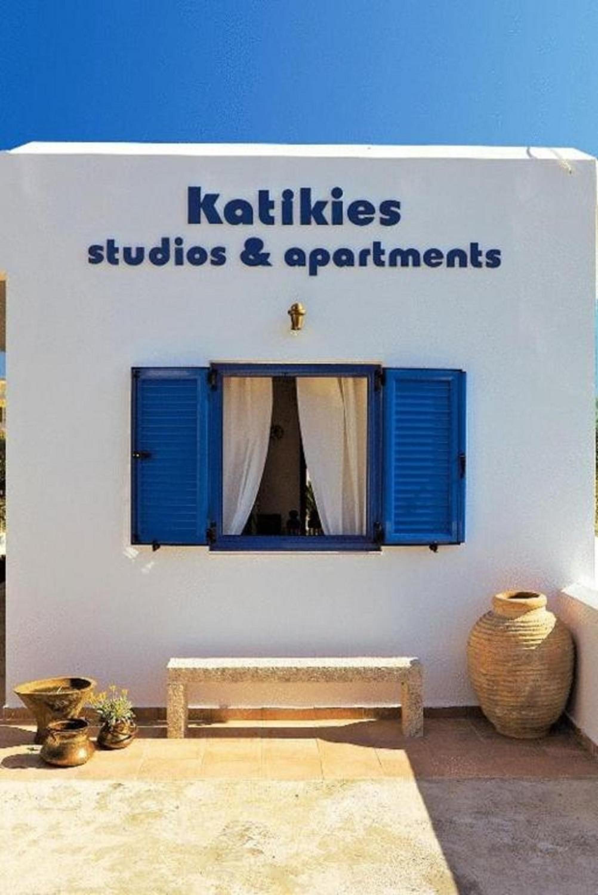 A building with a sign reading 'Katikies studios & apartments' and a window with blue shutters.
