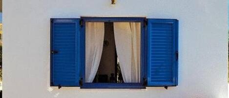 A building with a sign reading 'Katikies studios & apartments' and a window with blue shutters.