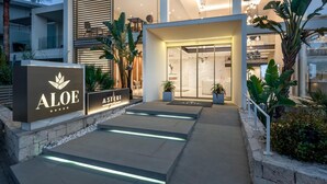 En moderne hotelindgang med et skilt for 'Aloe' og 'Asteri'.