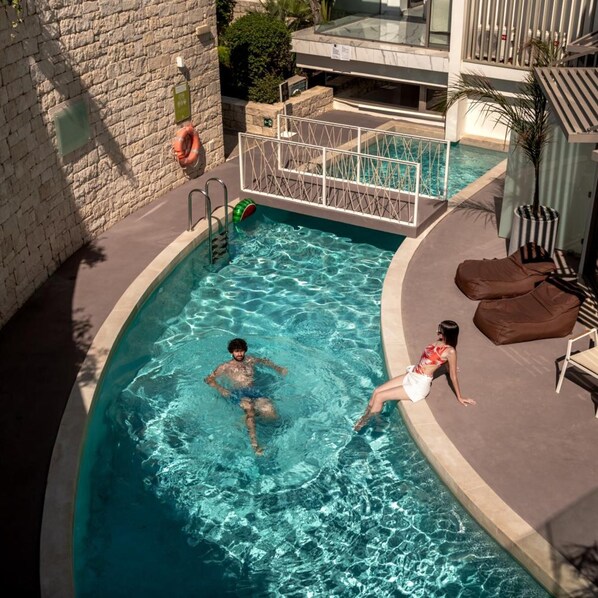A swimming pool with a glass barrier, a lifebuoy, and a lounge area with chairs.