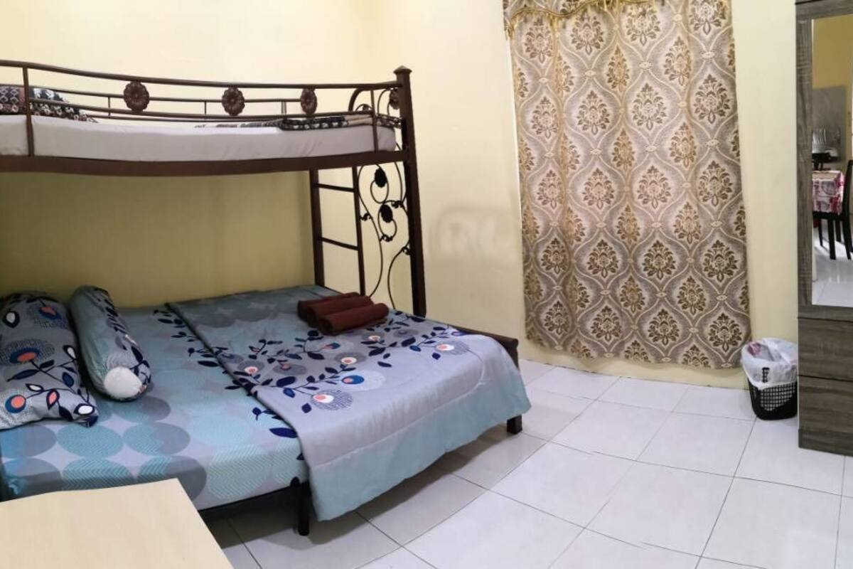 Un lit superposé avec une couvre-lit et des oreillers à motifs, une petite table de chevet et un rideau à motifs.