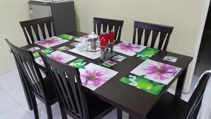 Un tavolo da pranzo con sottopiatti floreali, una caffettiera e tovaglioli rossi.