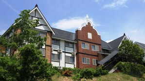 A modern building with a brick facade, multiple windows, and a sloped roof. - Petit Hotel Paddington House (Yamanouchi)