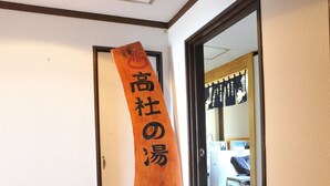 A hallway with a wooden sign, a mirror, and a door leading to another room. - Petit Hotel Paddington House (Yamanouchi)