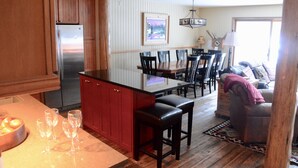 Una cocina con refrigerador de acero inoxidable, armarios de madera y un comedor con mesa y sillas.
