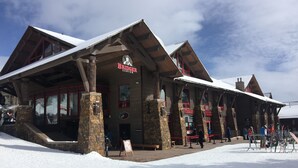 Un edificio rústico con fachada de madera, pilares de piedra y techo cubierto de nieve.