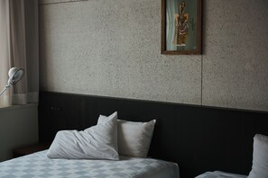 Habitación de hotel con cama, almohadas, cabecera, un cuadro en la pared y una ventana con cortinas.
