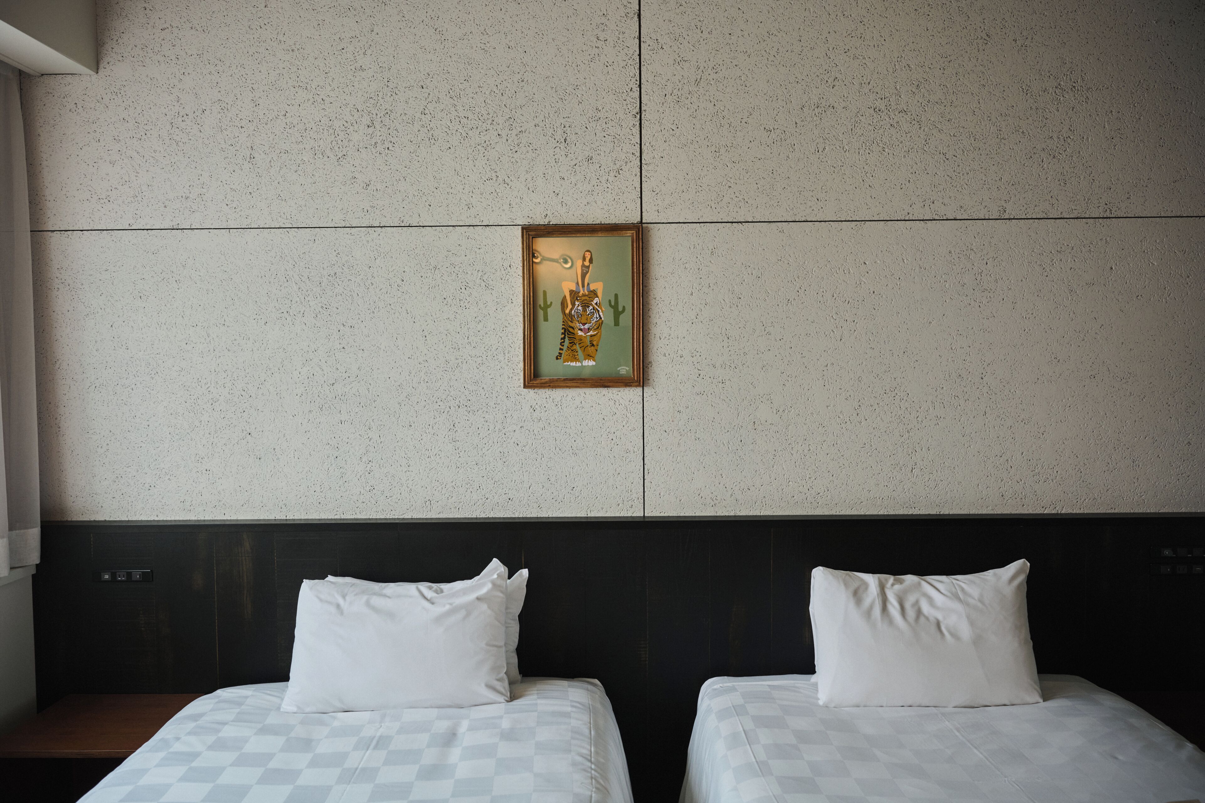 A hotel room with two beds, a headboard, and a wall-mounted artwork.