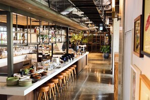 Una zona de bar con taburetes, estantes llenos de botellas y una barra larga.