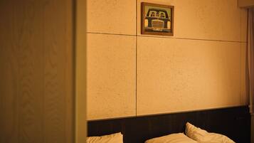 A hotel room with a bed, a headboard, and a wall-mounted picture.