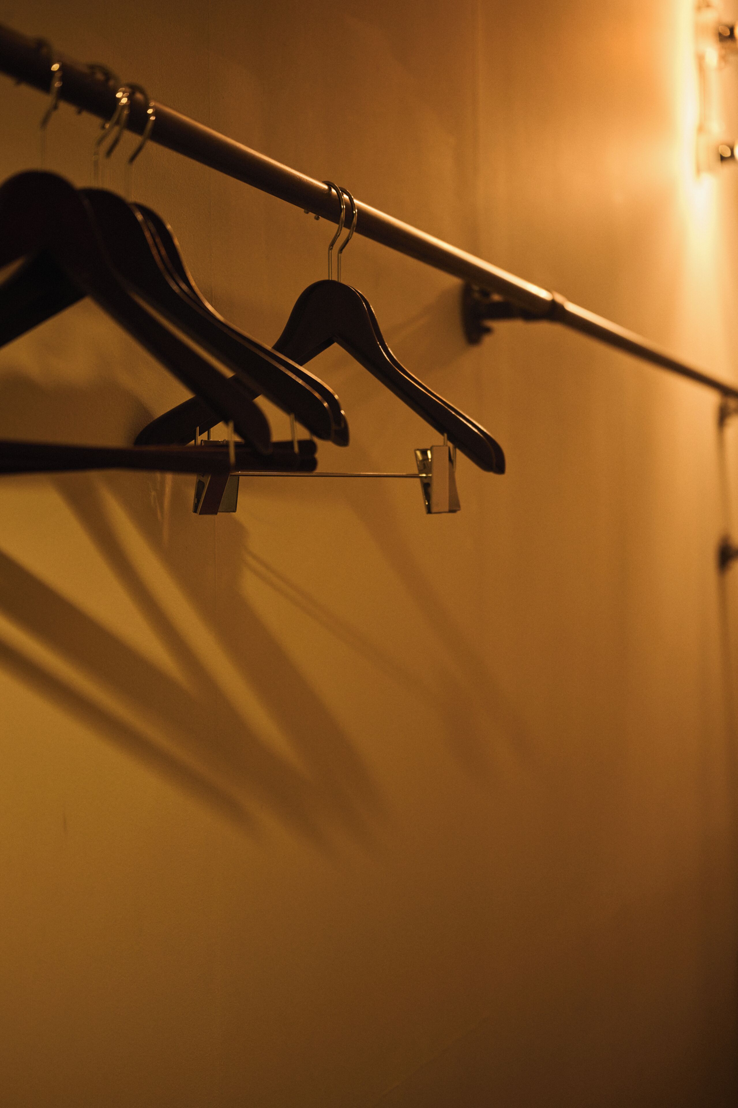 A wall with a metal rod and two black hangers.