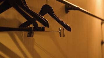 A wall with a metal rod and two black hangers.