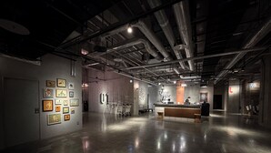 An interior space with a reception desk, framed artwork on the walls, and exposed ductwork on the ceiling. - The HOTEL Well-hub Haneda (Kawasaki)