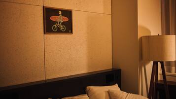 Quarto de hotel com cama, almofadas, um quadro pendurado na parede e um abajur.